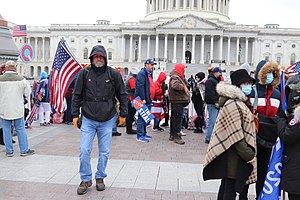 A QAnon emblem (upper left) is raised during the 2021 Capitol attack.