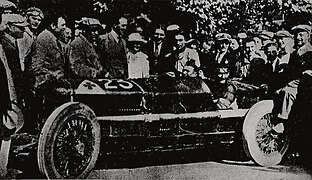 Foto di un uomo alla guida di un'auto circondato dalla folla.