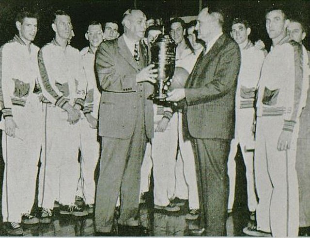 Adolph Rupp accepts the 1948 NCAA championship trophy.