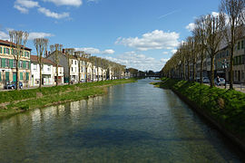 Photographie d'une rivière bordée d'arbres depuis un pont.