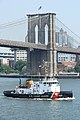 Coast guard vessel passes Brooklyn Bridge