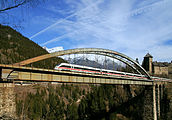 24. KWDer ÖBB-EuroCity 562 auf der Trisannabrücke (Arlbergbahn). Im Hintergrund das Schloss Wiesberg in der Gemeinde Tobadill, Tirol.