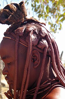 The use of red clay as a form of dry shampoo in the hair of a Himba woman. Himbawoman.JPG