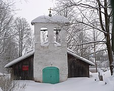Photographie d'une église entourée de neige, en bois avec le clocher en pierre blanche.