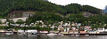 Bâtiments visibles sur un rivage avec une forêt au-dessus