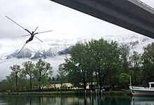 Vor dem Hintergrund eines wolkenverhangenen und schneebedeckten Bergkamms wird die moderne Bronzeskulptur «Grand Archange» (zu deutsch: Grosser Erzengel) gezeigt. Der Engel hat keine klassischen Flügel. Diese wurden vom Künstler durch gekreuzte Metallstangen ersetzt. Die Figur ist mit dünnen Stahlseilen, die für alle Betrachter kaum zu sehen sind, am Goldswil-Viadukt befestigt und scheint dadurch beinahe frei in der Luft zu schweben.