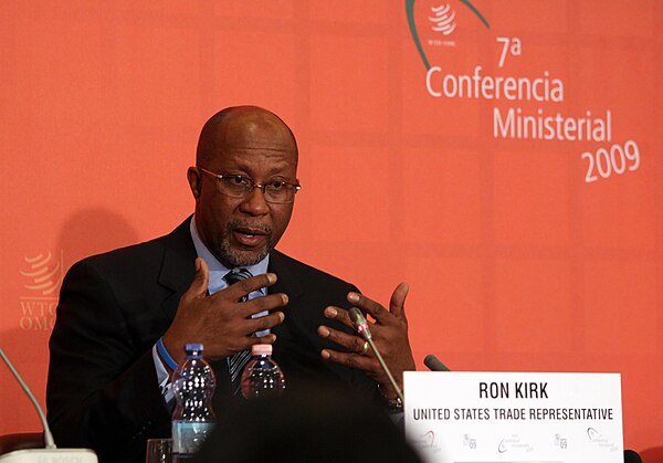 Kirk speaking at a press conference at the end of the 7th WTO Ministerial Conference
