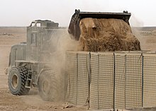 A front end loader filling HESCO barriers during a project at Camp Bastion US Navy 090411-N-8547M-011 A Seabee assigned to Naval Mobile Construction Battalion (NMCB) 5 uses an up-armored front end loader to fill HESCO barriers during a project at Camp Bastion.jpg