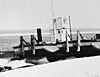 Övre verk och rökstack av bogserbåt Radium Lad, synlig bakom en pråm, vid Fort Franklin - N-1980-002-0045.jpg