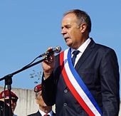 Portrait rapproché d'un homme portant une écharpe tricolore.