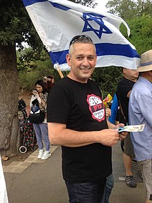 Yonathan Tadmor at the Yaka square. Next to him, three Japanese tourists are recording the demonstration. Jerusalem, 16 July 2018. A Demonstration of Disabled People July 2018 3.jpg