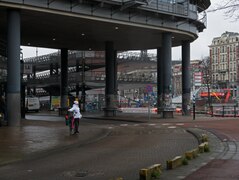 Amsterdam photo 2023 - a biking woman is searching her way; In the background the empty bicycle storage & Prins Hendrikkakde. Location, west side Central Station. Free download street photography, Fons Heijnsbroek, CCO Ne.tif