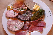 Brotzeitplatte, clockwise from the mustard: Brawn, liver sausage, butter, cucumber, smoked meat, white Pressack (head cheese), Göttinger and red Pressack in the middle.