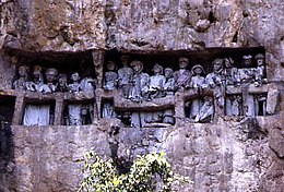 A stone-carved Toraja cliff burial site. Tau tau (effigies of the deceased) look out over the land. Burial Site 2.jpg