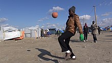 A young migrant dribbling a ball at the camp during October 2015 Calais2015m.jpg