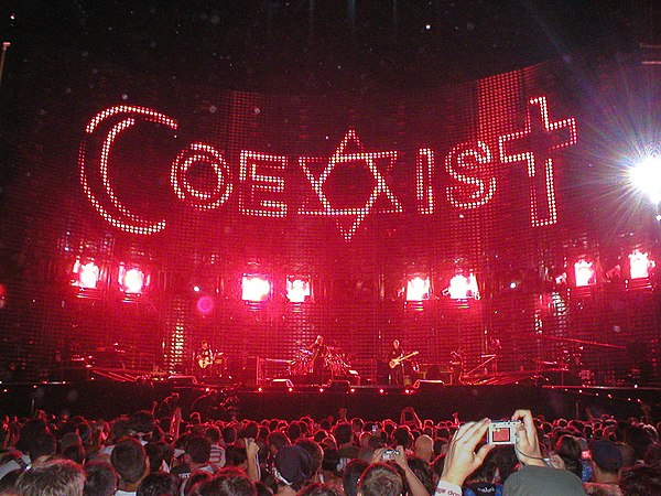 The symbols of Islam, Judaism, and Christianity form the word "CoeXisT" during a performance of "Sunday Bloody Sunday".