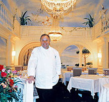 Eckart Witzigmann at the Aubergine in Munich, behind him murals by Rainer Maria Latzke Eckart Witzigmann Aubergine.jpg