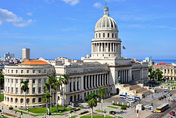 The National Capitol of Cuba, seen from a rooftop to its southeast. The building and its dome make up the entirety of the center of the image, running from the foreground in the lower left to the background in the middle-right.