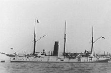 three-masted, white-hulled, single-funnelled warship at anchor