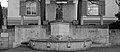 Jakob Probst (1880–1966), Wehrmannsdenkmal 1923–1934 für die Grippe- und Unfalltoten aus der Baseler Landschaft (Grippe-Epidemie 1918) am Regierungsgebäude (Südseite) in Liestal. Seine Urne (Inschrift) befindet sich links neben dem Brunnen.