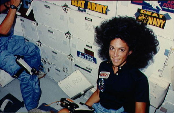 Resnik on the middeck of Space Shuttle Discovery during the STS-41-D mission, with an "I love Tom Selleck" sticker on her locker. A handwritten card r