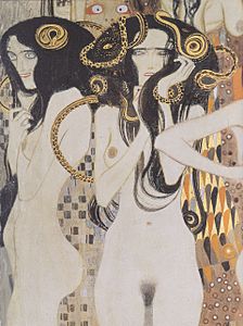 Deux femmes nues vues de profil et de face avec une abondante chevelure noire où sont incrustés des serpents dorés.