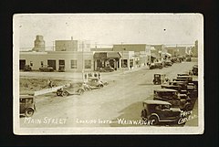 View of busy commercial street in town with stores and shops in 1930.