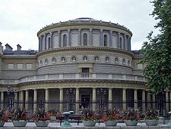 A rotunda with Corinthian colonnades, fronted with railings and plants.