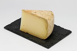 Fotografie a unei felii de brânză prezentată pe o ardezie.