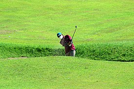 Peserta Turnamen golf melakukan sand wedge di hole ketiga saat ia menyelesaikan dengan keunggulan dua pukulan dengan satu grup tersisa untuk bermain di hole ketiga selama putaran turnamen golf di Lapangan Bukit Darmo Golf Surabaya