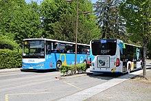 Photographie en couleurs d’un autocar du réseau de Rumilly et d’un autobus du réseau d’Annecy, les deux dans des sens opposés.