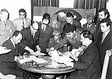 Assad (sitting on the right side) signing the Federation of Arab Republics in Benghazi, Libya, on 18 April 1971 with President Anwar al-Sadat (sitting left) of Egypt and Colonel Muammar al-Qaddafi of Libya (sitting in the centre). Sadat Qaddafi Assad 1971.jpg