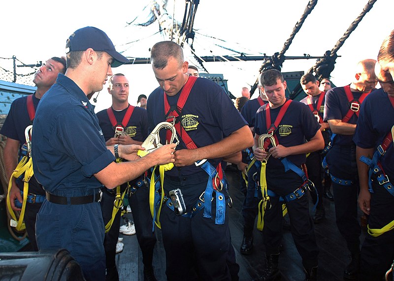 File:US Navy 050823-N-9076B-002 Electronics Technician 2nd Class Edwin Dillaby, left, helps a chief selectee with a safety harness during an up and over drill were the selectees climb the mast and come down the other side aboard USS.jpg