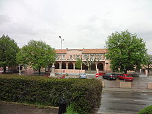 La façade de l'école, peinte en rose, est composée du préau ouvrant par des arcades sur la cour, surmonté d’un étage de fenêtres des salles de classe