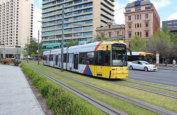 A tram running on green track at Victoria Square.