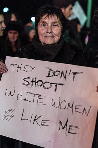 A protester holds a sign reading "They don't shoot white women like me" at a Black Lives Matter protest in the wake of the non-indictment of a New York City police officer for the death of Eric Garner
