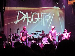 La banda Daughtry tocando en el escenario frente a un telón de fondo que muestra su nombre