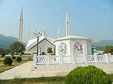 Kleines weißes Mausoleum vor einer Moschee aus weißem Marmor