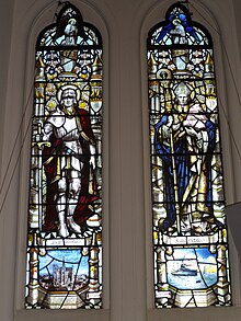 Main WWI memorial window by Archibald Keightley Nicholson. The left-hand pane shows Saint Martin above Amiens Cathedral. The right-hand pane shows Saint Nicholas above Scapa Flow and battleships of the Grand Fleet Main WWI memorial window in Busbridge Church 03.jpg