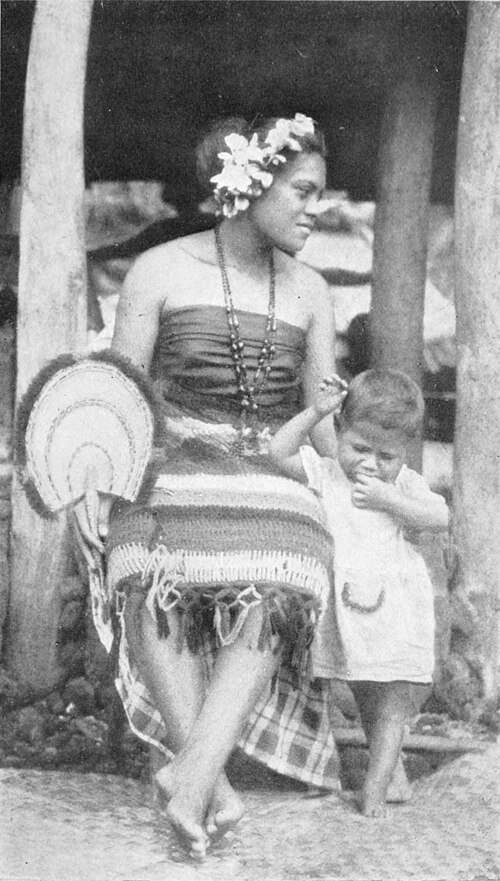 A photo of a woman seated, with a child leaning against her
