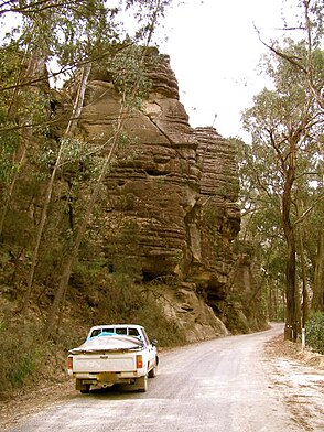 Braidwood Road (1856 route) ascending the escarpment east of Nerriga, in 2006, prior to its upgrading to modern highway standard. The cliff face shown survives, alongside the upgraded road. This location is just a little west of where the 1856 and 1841 routes merged at Bulee Gap. Nerriga Road.jpg