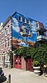 A large painting on the side of a building showcasing all major landmarks and the flag of Rotterdam.