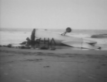 Rear fuselage inverted on Seven-Mile Beach. The fin and rudder have been folded down parallel to the tailplane. SevenMileBeach1946 2.png