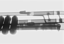 X-ray image of a trumpet, casting the tubing of the trumpet into a black, white, and grey scale..