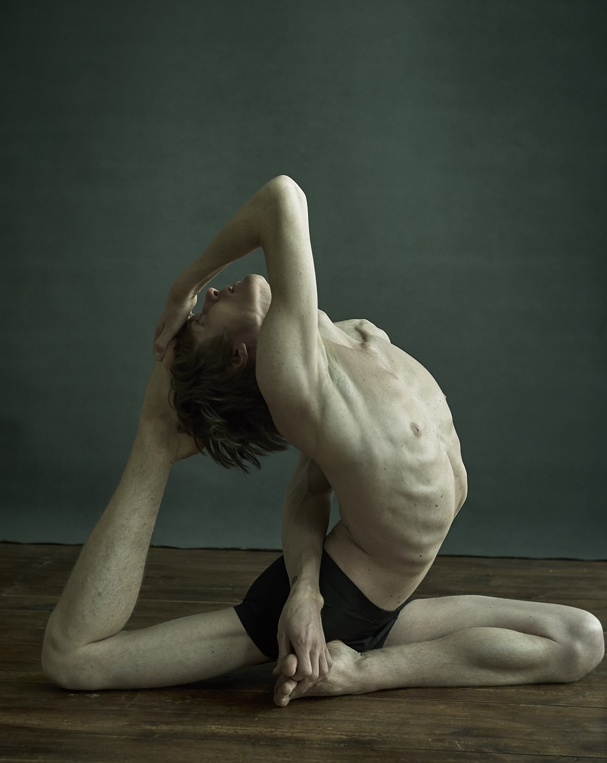 Young woman practicing yoga doing one legged king pigeon pose in dark room.  Eka Pada Rajakapotasana asana. Wellness and healthy lifestyle. - Album  alb9817120