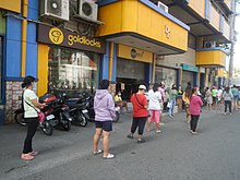 Shoppers falling in line outside a supermarket in Bulacan in March 2020 which was under ECQ at that time while observing social distancing 82902Coronavirus pandemic in Baliuag, Bulacan 10.jpg