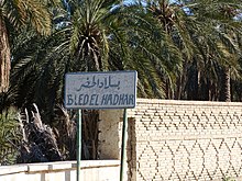 Cartel bilingüe frente a palmeras.