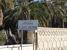 Panneau bilingue devant des palmiers.