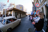 West German children applaud as East German visitors drive through Checkpoint Charlie and take advantage of relaxed travel restrictions to visit the West.