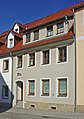 Wohnhaus in geschlossener Bebauung, am Haus Relief mit Schmiedeszene als Hausemblem